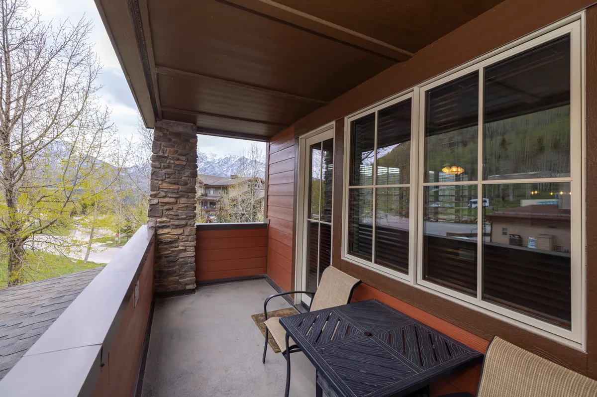 A serene terrace scene featuring a stone pillar, a table and chairs, and an expansive mountain view. The setup invites guests to unwind outdoors, enjoy leisurely meals, or simply take in the natural beauty and fresh mountain air. The peaceful ambiance is ideal for moments of relaxation amidst nature.