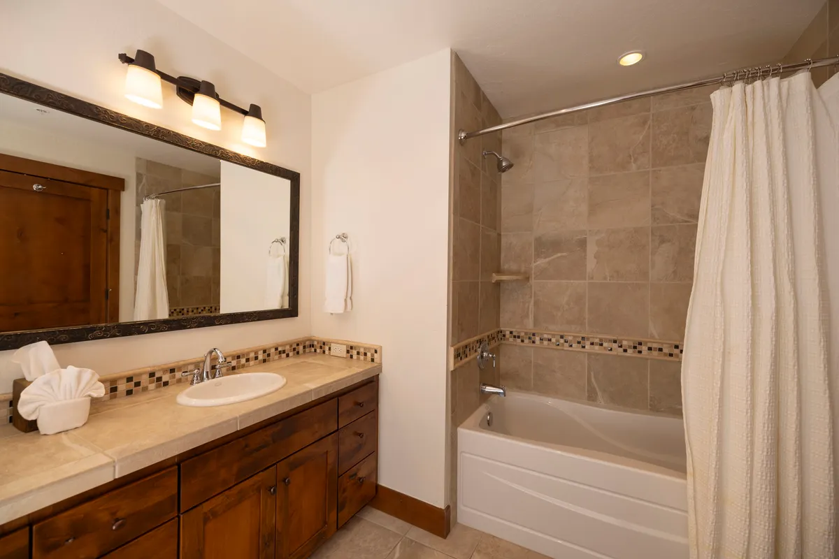 A serene bathroom featuring a vanity with a mirror, a spacious bathtub, and a separate shower area. The space is well-lit, clean, and designed for relaxation and refreshing routines, with a calming color scheme that enhances the sense of tranquility.