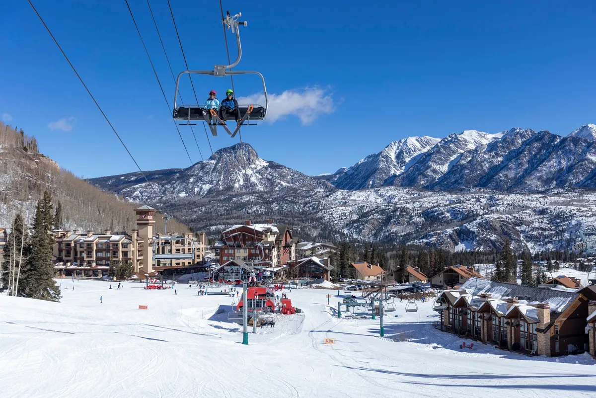 A lively exterior scene showcasing the ski lift ascending snow-covered mountains, with skiers making their way down the slopes and resort buildings nestled at the base. The image radiates an exciting, adventurous vibe while highlighting the property's proximity to all the winter resort action.